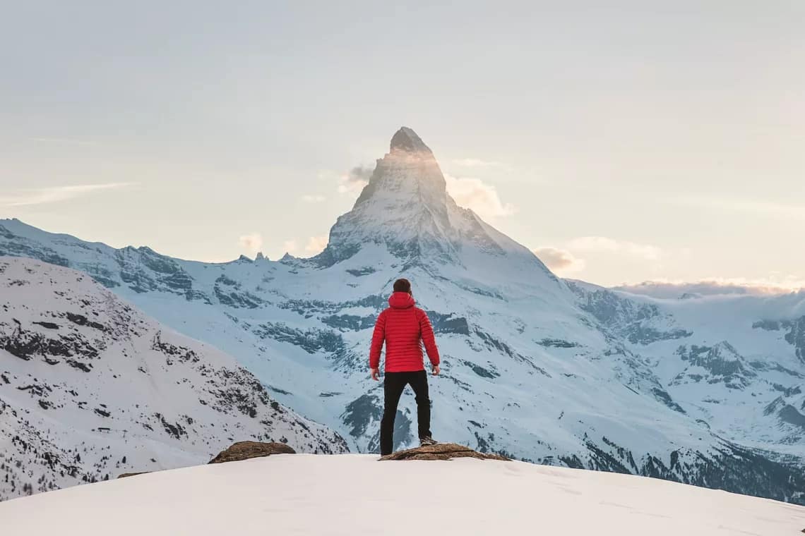 person in red hoodie with good habit standing on snowy mountain during daytime