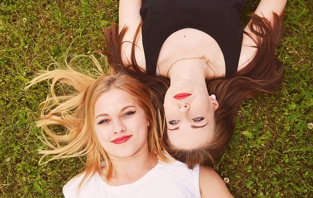 two women lying on the grass thinking about how much money they're spending on wine